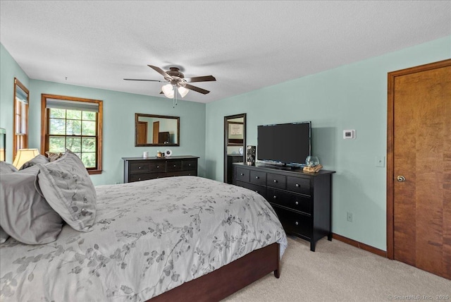 bedroom with baseboards, a ceiling fan, a textured ceiling, and light colored carpet