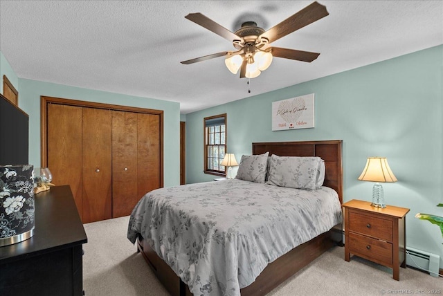 bedroom with ceiling fan, a textured ceiling, light colored carpet, baseboard heating, and a closet