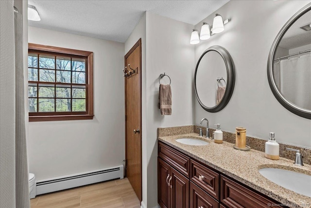 full bathroom featuring double vanity, a sink, wood finished floors, and baseboard heating