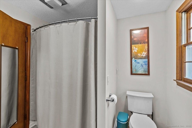 bathroom with toilet, a textured ceiling, visible vents, and a shower with shower curtain