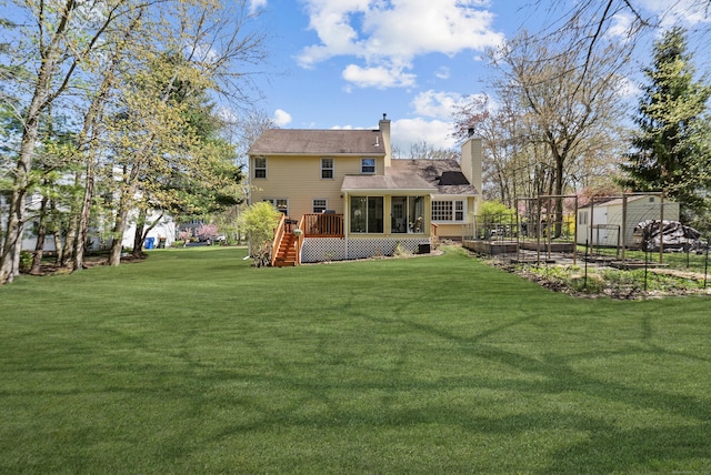 view of yard featuring a deck, stairs, a sunroom, and a vegetable garden