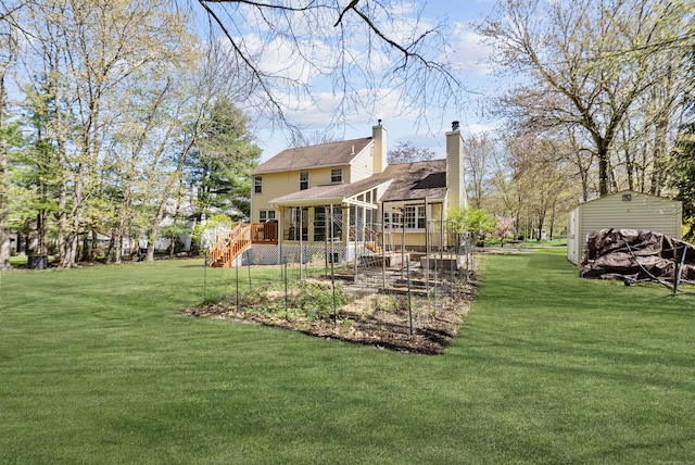 back of house featuring a chimney, a lawn, a deck, a sunroom, and stairs