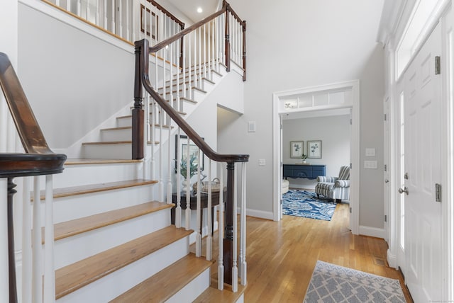 entrance foyer with stairway, hardwood / wood-style floors, baseboards, and a high ceiling