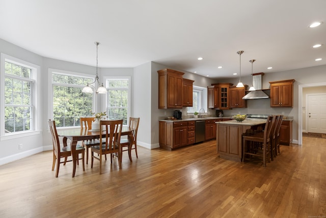 kitchen with baseboards, a kitchen island, wall chimney exhaust hood, and dishwasher