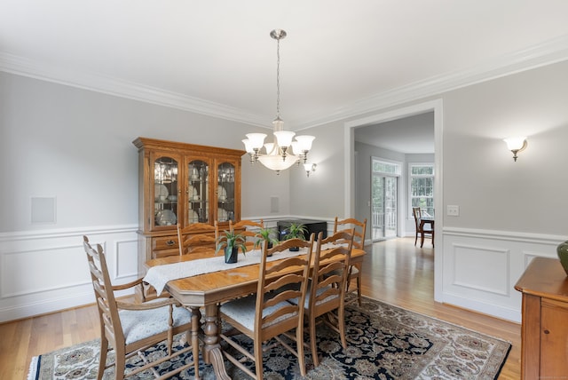 dining room with light wood-style floors, a chandelier, and crown molding