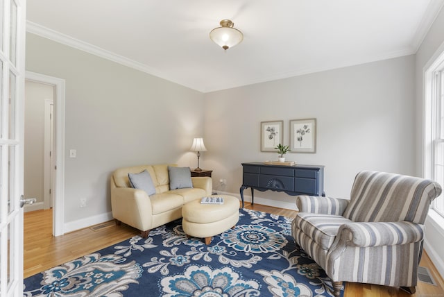 living area featuring ornamental molding, baseboards, visible vents, and wood finished floors
