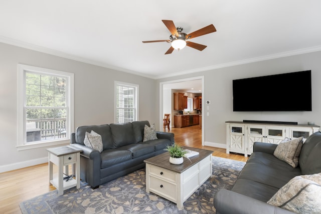 living area with ornamental molding, baseboards, a ceiling fan, and wood finished floors