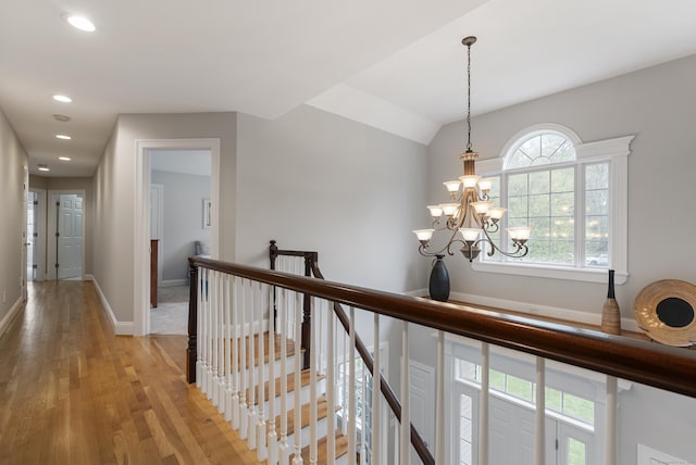 hall featuring light wood finished floors, an inviting chandelier, an upstairs landing, baseboards, and recessed lighting