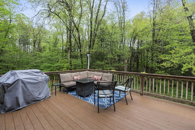 wooden terrace with an outdoor hangout area, a wooded view, and grilling area