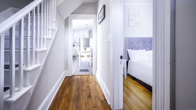 corridor with baseboards, dark wood finished floors, and stairway