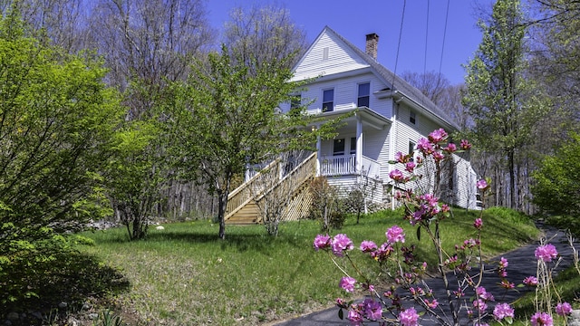 exterior space with stairway, covered porch, and a chimney