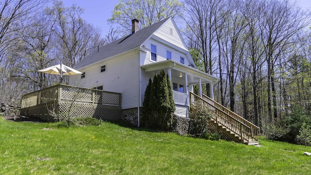 view of side of property with a chimney, a yard, stairway, and covered porch