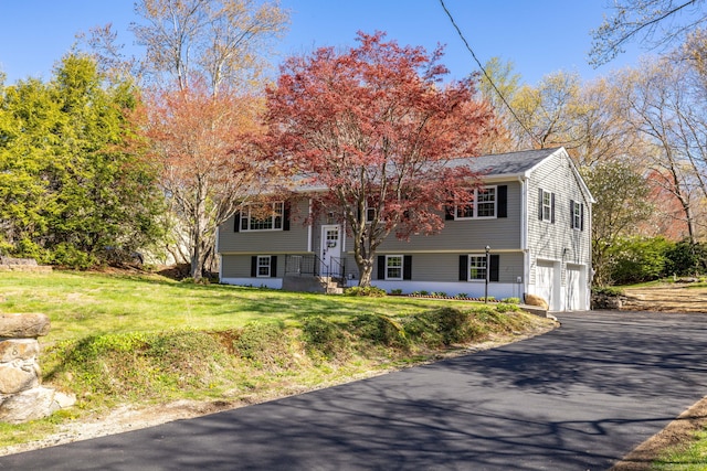 split foyer home featuring a garage, a front lawn, and aphalt driveway