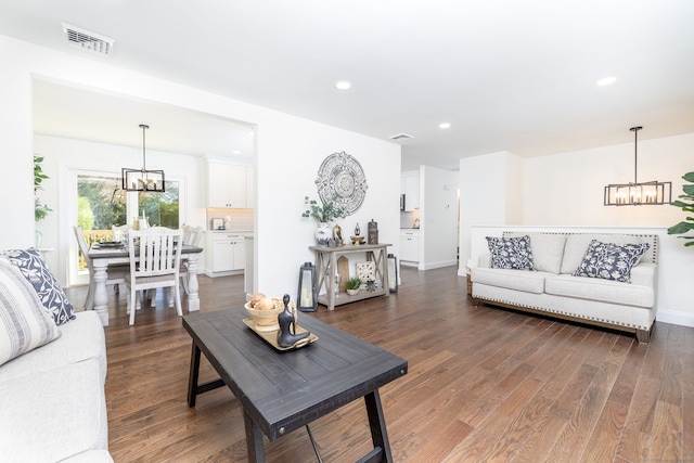 living room with an inviting chandelier, recessed lighting, wood finished floors, and visible vents