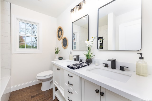 bathroom with double vanity, toilet, baseboards, and a sink