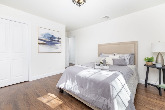 bedroom with baseboards, visible vents, wood finished floors, and a closet