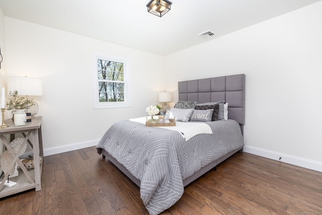 bedroom with baseboards, wood finished floors, and visible vents