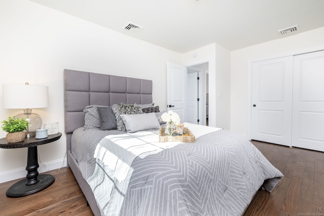 bedroom featuring baseboards, visible vents, dark wood finished floors, and a closet
