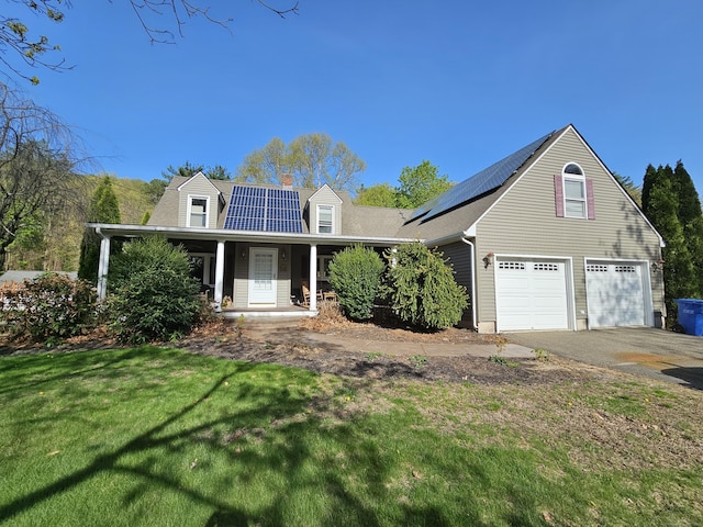view of front of home featuring roof mounted solar panels, covered porch, a chimney, and a front lawn