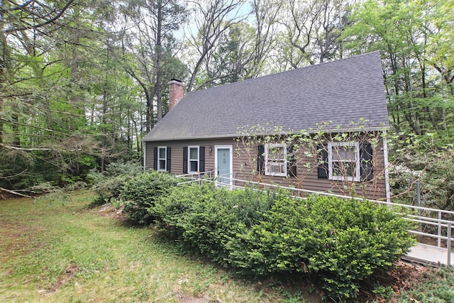 view of front facade featuring a chimney and a shingled roof