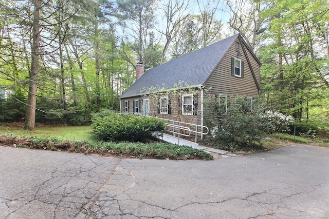view of front facade with a chimney and a shingled roof