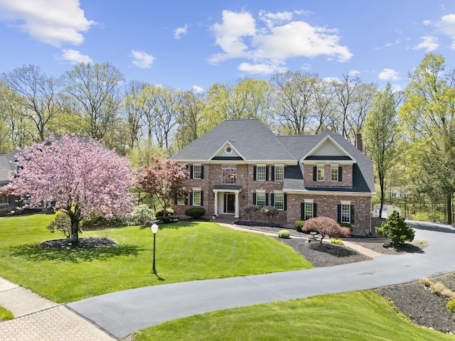 view of front of property featuring a chimney, a front lawn, and brick siding
