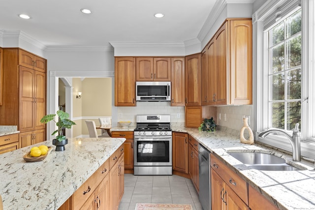 kitchen with light stone counters, a sink, tasteful backsplash, and stainless steel appliances