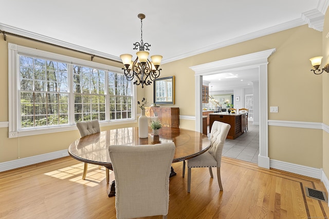 dining area with plenty of natural light, ornamental molding, a chandelier, and visible vents