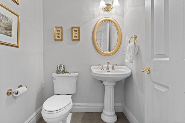 bathroom with toilet, baseboards, and tile patterned flooring