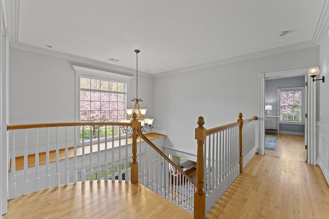 hall featuring visible vents, wood finished floors, an upstairs landing, an inviting chandelier, and ornamental molding