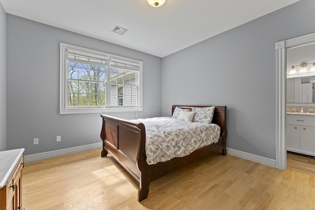 bedroom with a sink, ensuite bath, light wood-style flooring, baseboards, and visible vents