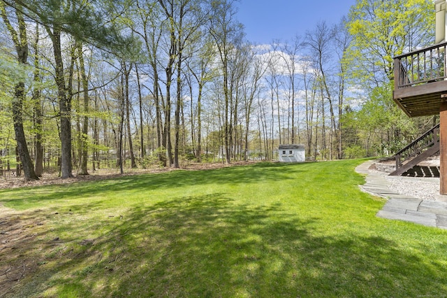 view of yard featuring an outdoor structure, a storage shed, stairway, and a deck