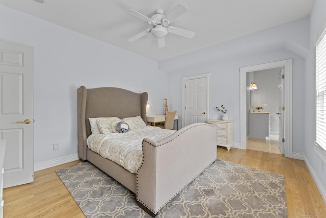 bedroom featuring light wood-style floors, a ceiling fan, baseboards, and ensuite bathroom