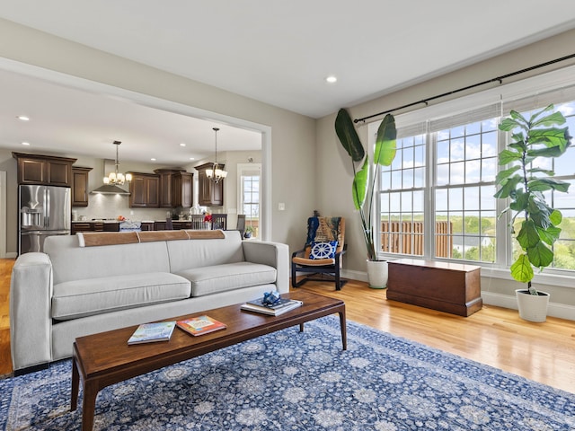 living area featuring baseboards, light wood-style floors, an inviting chandelier, and recessed lighting