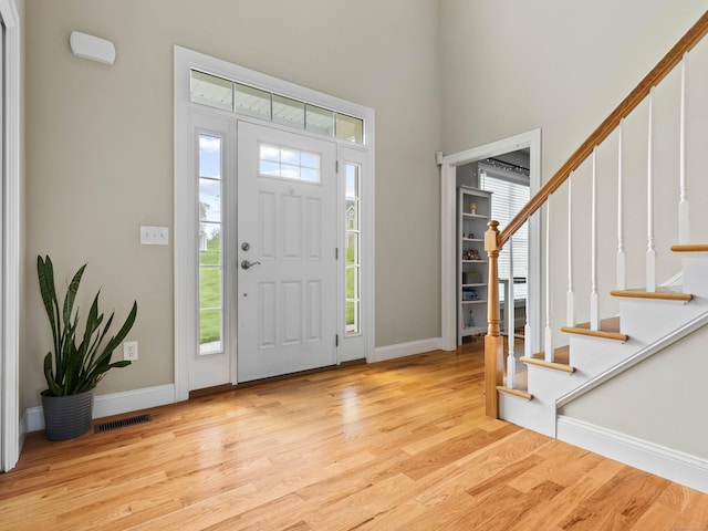 entryway with stairway, baseboards, visible vents, and wood finished floors