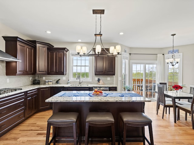 kitchen with a chandelier, a sink, dark brown cabinetry, appliances with stainless steel finishes, and tasteful backsplash