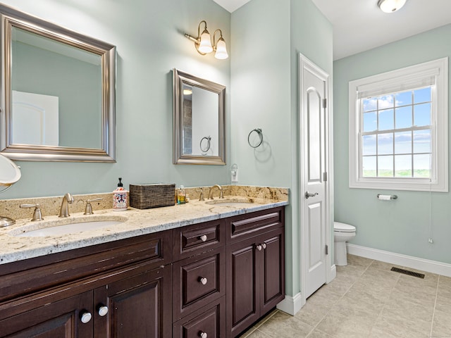 bathroom with double vanity, baseboards, tile patterned flooring, and toilet