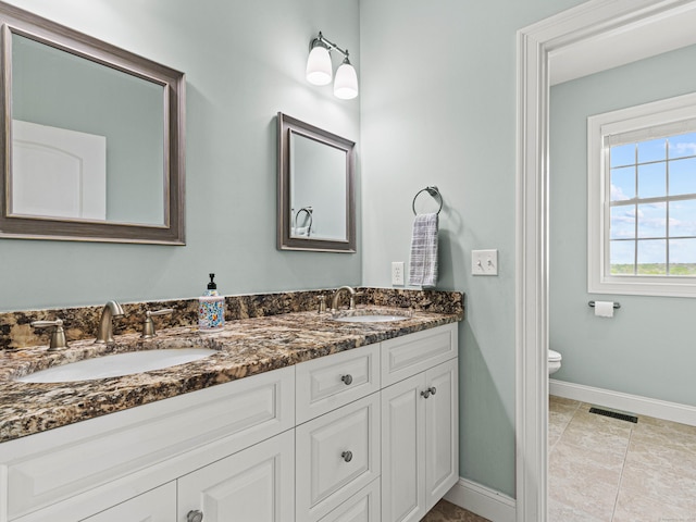 full bath with baseboards, double vanity, and toilet