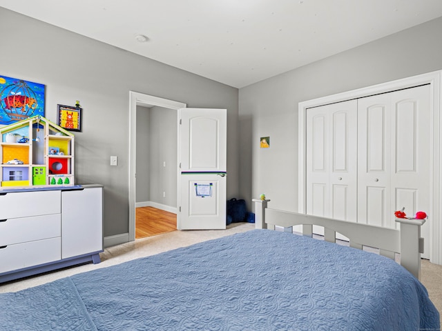 bedroom with light carpet, baseboards, and a closet