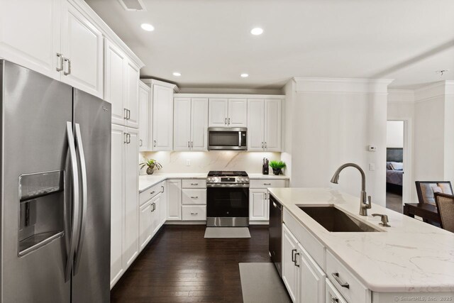 kitchen with stainless steel appliances, dark wood-style floors, a sink, and white cabinetry