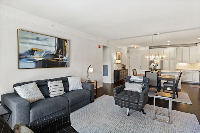 living area featuring electric panel, crown molding, baseboards, dark wood-style floors, and a chandelier