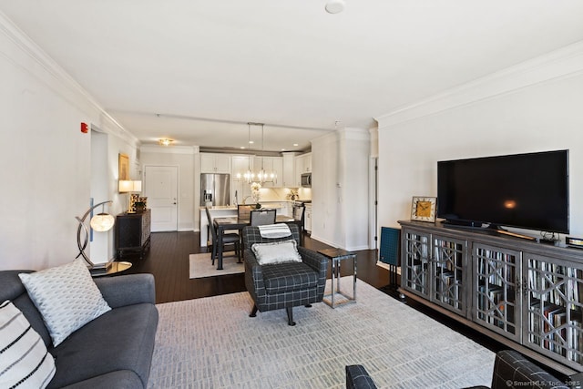 living area with ornamental molding, dark wood finished floors, and a notable chandelier