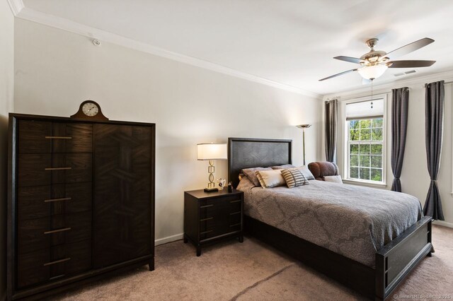 bedroom featuring light colored carpet, ornamental molding, baseboards, and a ceiling fan