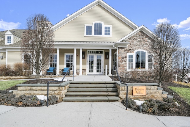 view of front of house with a porch, french doors, and stone siding