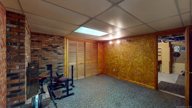 finished below grade area with baseboards, a paneled ceiling, and carpet