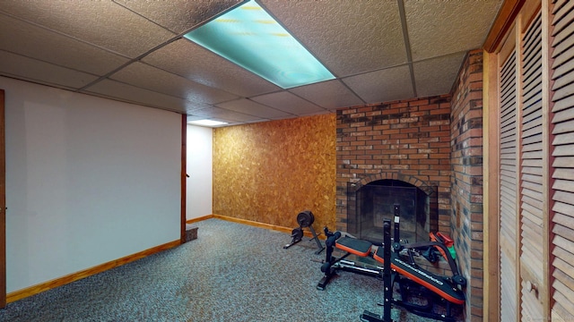 workout area with carpet floors, baseboards, a paneled ceiling, and a fireplace