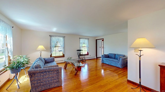 living area with light wood-type flooring, a baseboard radiator, baseboards, and baseboard heating