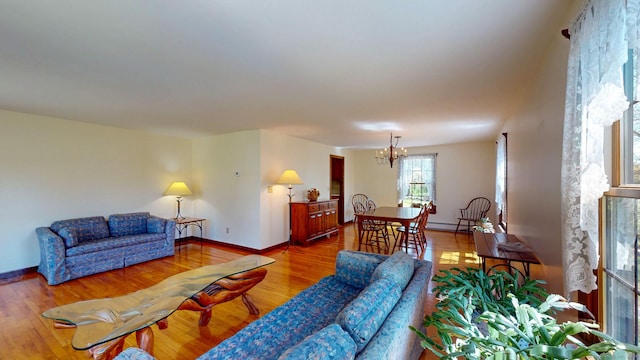 living room with an inviting chandelier, baseboards, and wood finished floors
