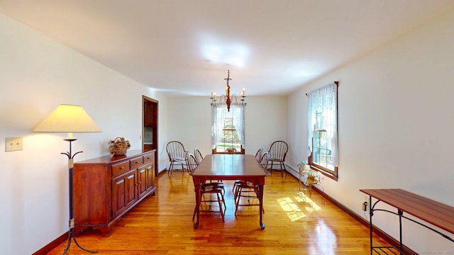 dining area featuring baseboards, a notable chandelier, and light wood-type flooring