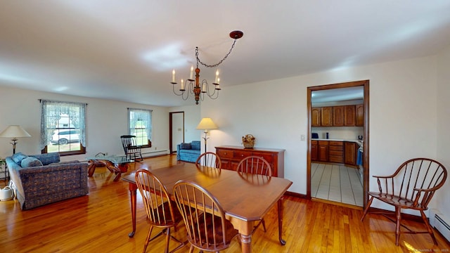 dining space with light wood-style floors, baseboard heating, and a chandelier